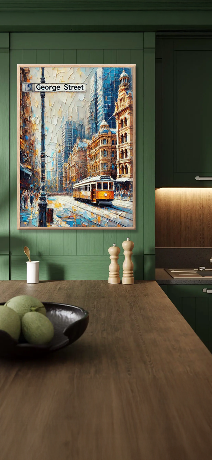 A green kitchen features a wooden countertop with a black bowl of green fruit, two pepper mills, and a painting of a city street with a tram labeled George Street on the wall.