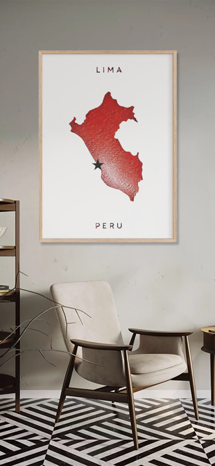 A framed map of Peru with a red silhouette and a star marking Lima hangs on a light-colored wall above a beige armchair in a modern, minimalist room.